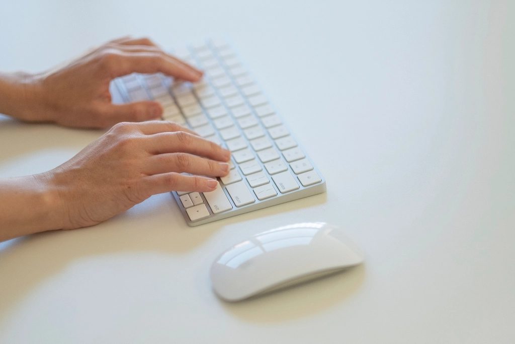 Hands typing on a keyboard at a desk
