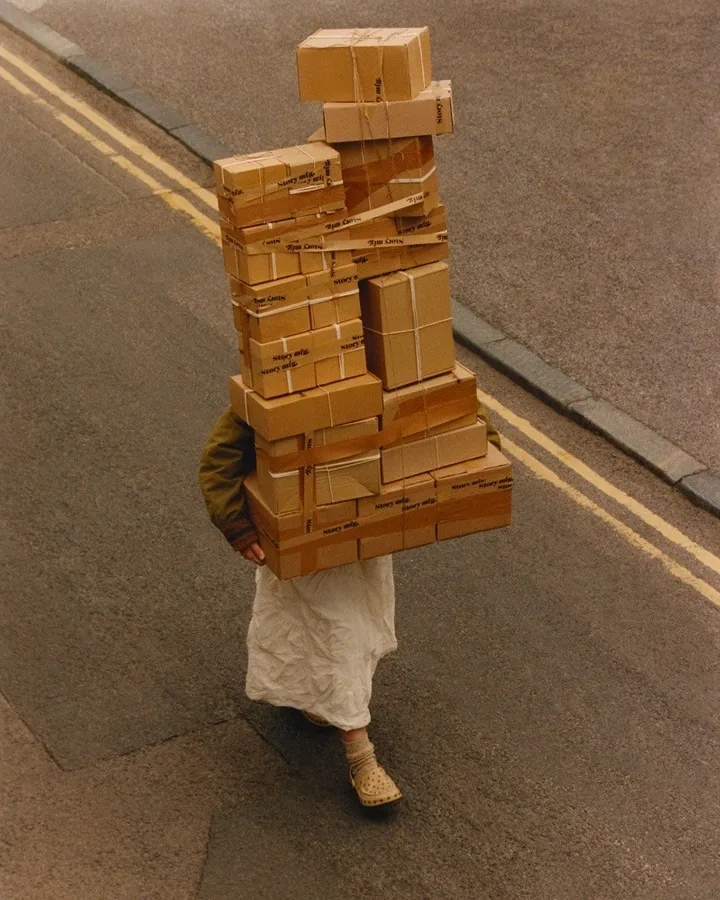 A shop owner smiling behind the counter with a stack of wrapped orders ready to go out